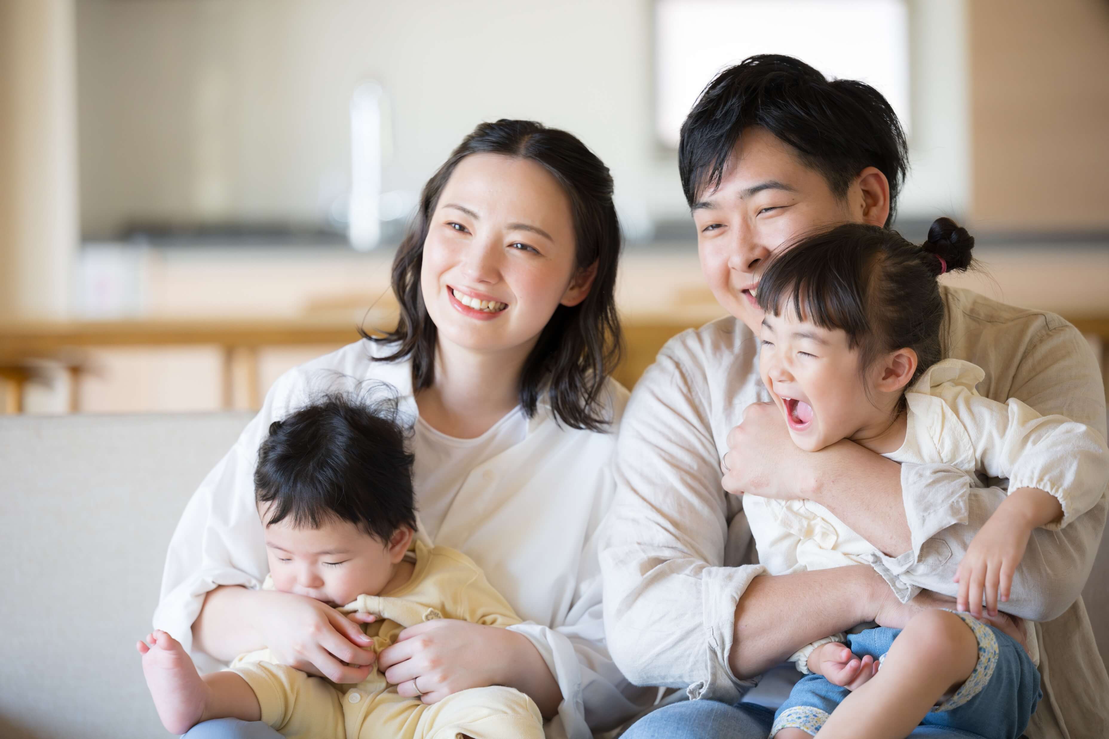 家族4人の画像、父親が娘を抱っこしており母親が息子を抱っこしている